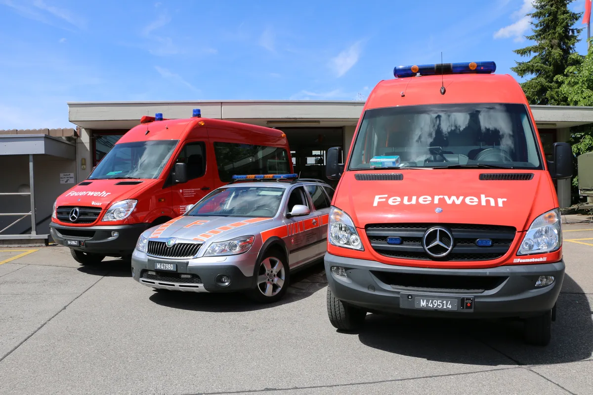 Drei Feuerwehrfahrzeuge auf einem Platz.